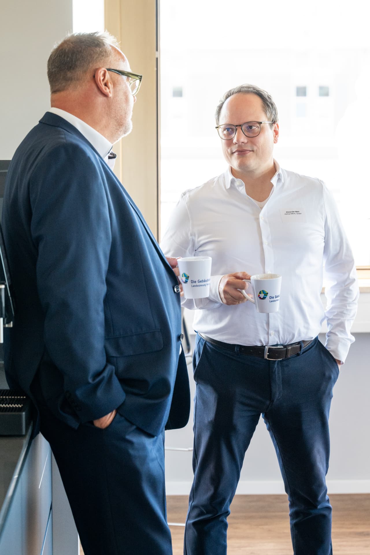 Zwei Gäste im Gespräch mit Kaffeetassen der Landesinnung