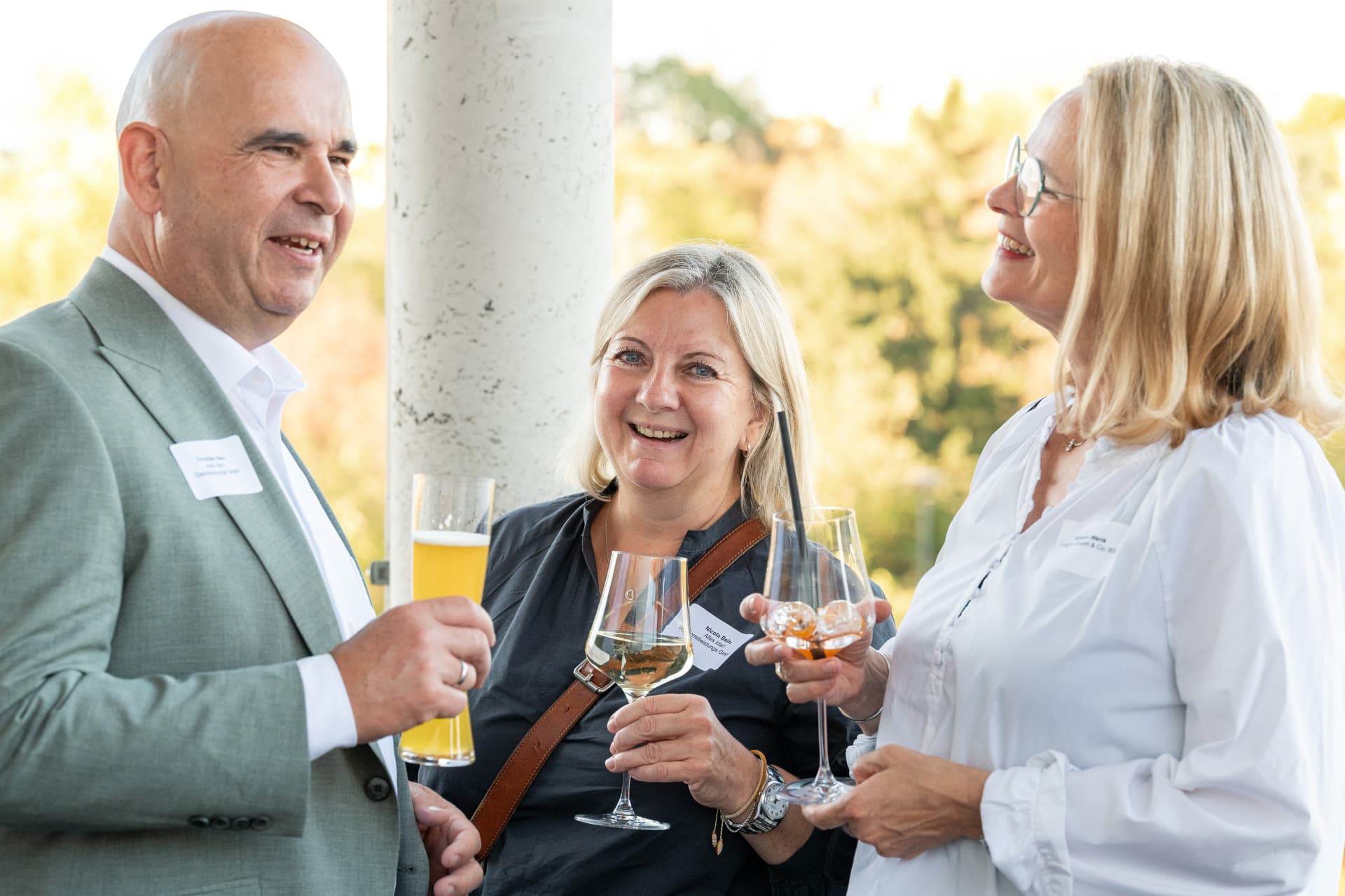 Drei Gäste mit Gläsern im entspannten Gespräch