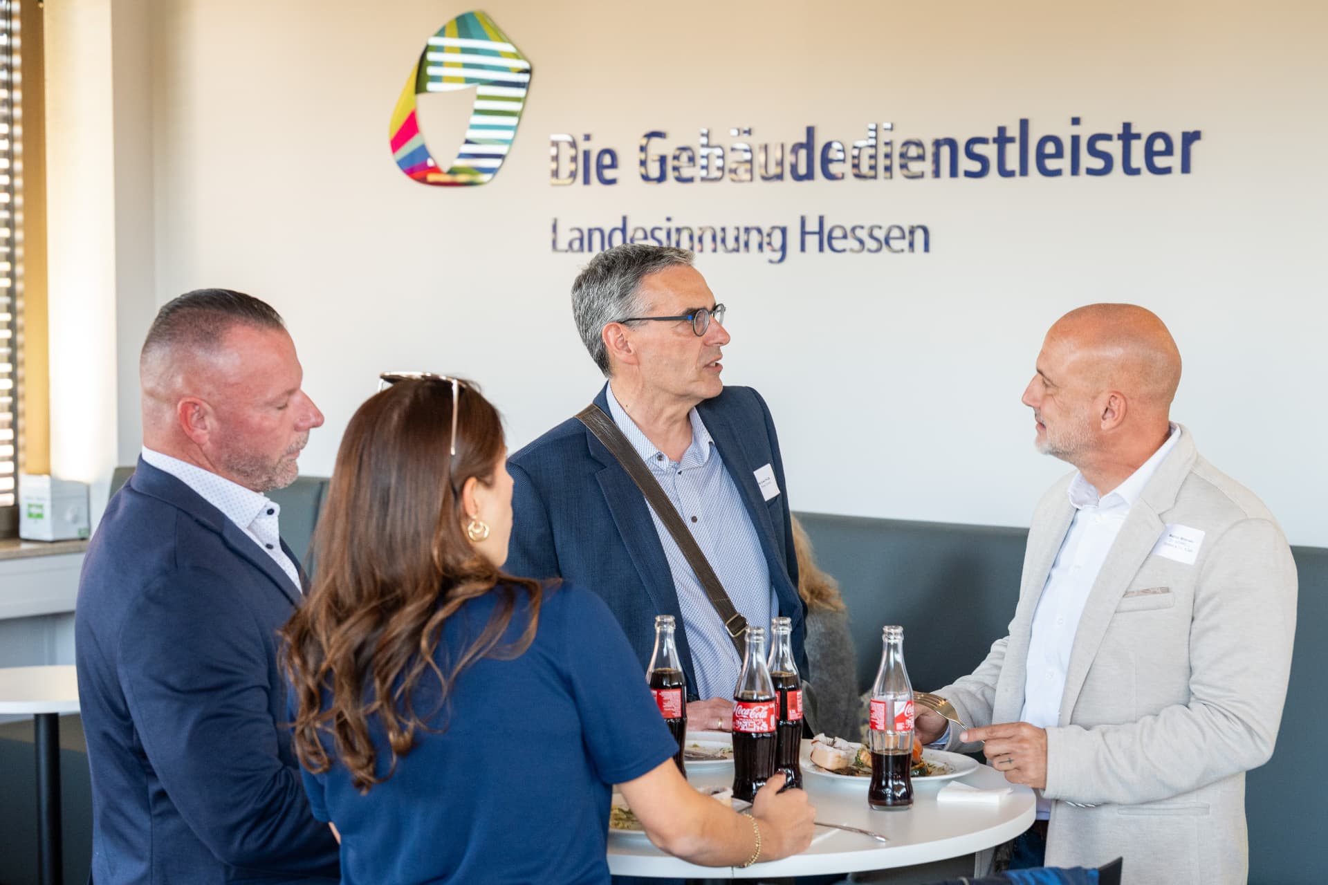 Gespräche am Tisch vor der Wand „Die Gebäudedienstleister Landesinnung Hessen“