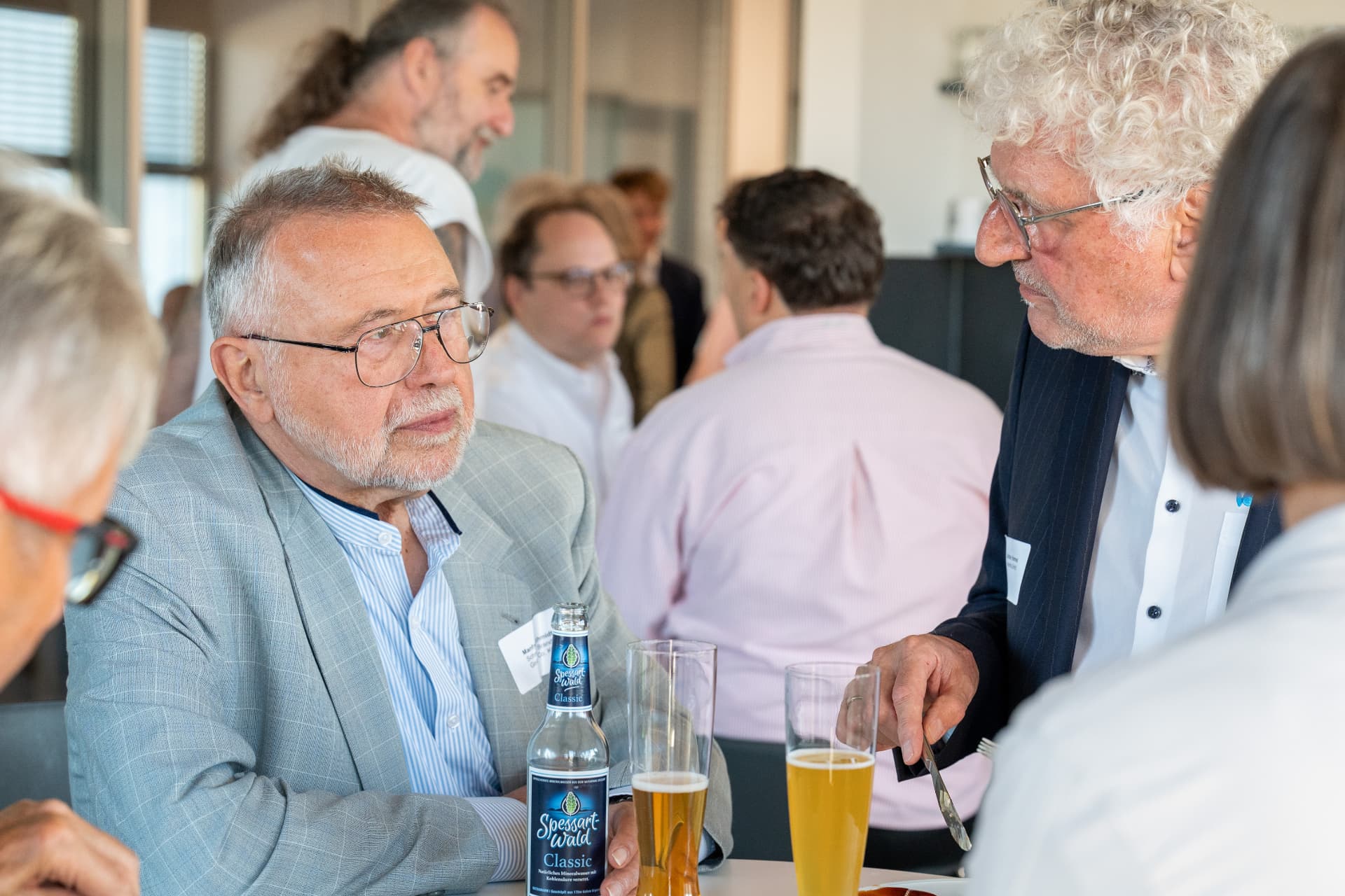 Gäste am Tisch im Gespräch bei Bier und Speisen